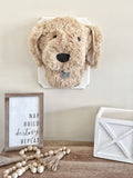A plush Puppy Dog Wall Mount handmade by ClaraLoo in an animal themed nursery. This stuffed dog is made with soft tan faux fur and crocheted accents. This plush puppy is mounted on a white wooden plaque.
