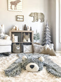 An adventure theme nursery with a plush gray bear rug made by ClaraLoo on the floor. A bear basket and fox basket made by ClaraLoo are on shelves in the background.