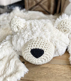 A plush polar bear rug made by ClaraLoo with cream colored crocheted accents and a black nose.