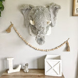 A plush elephant wall mount handmade by ClaraLoo in a safari themed nursery. This stuffed elephant is made of soft gray faux fur with a crocheted snout and tusks.